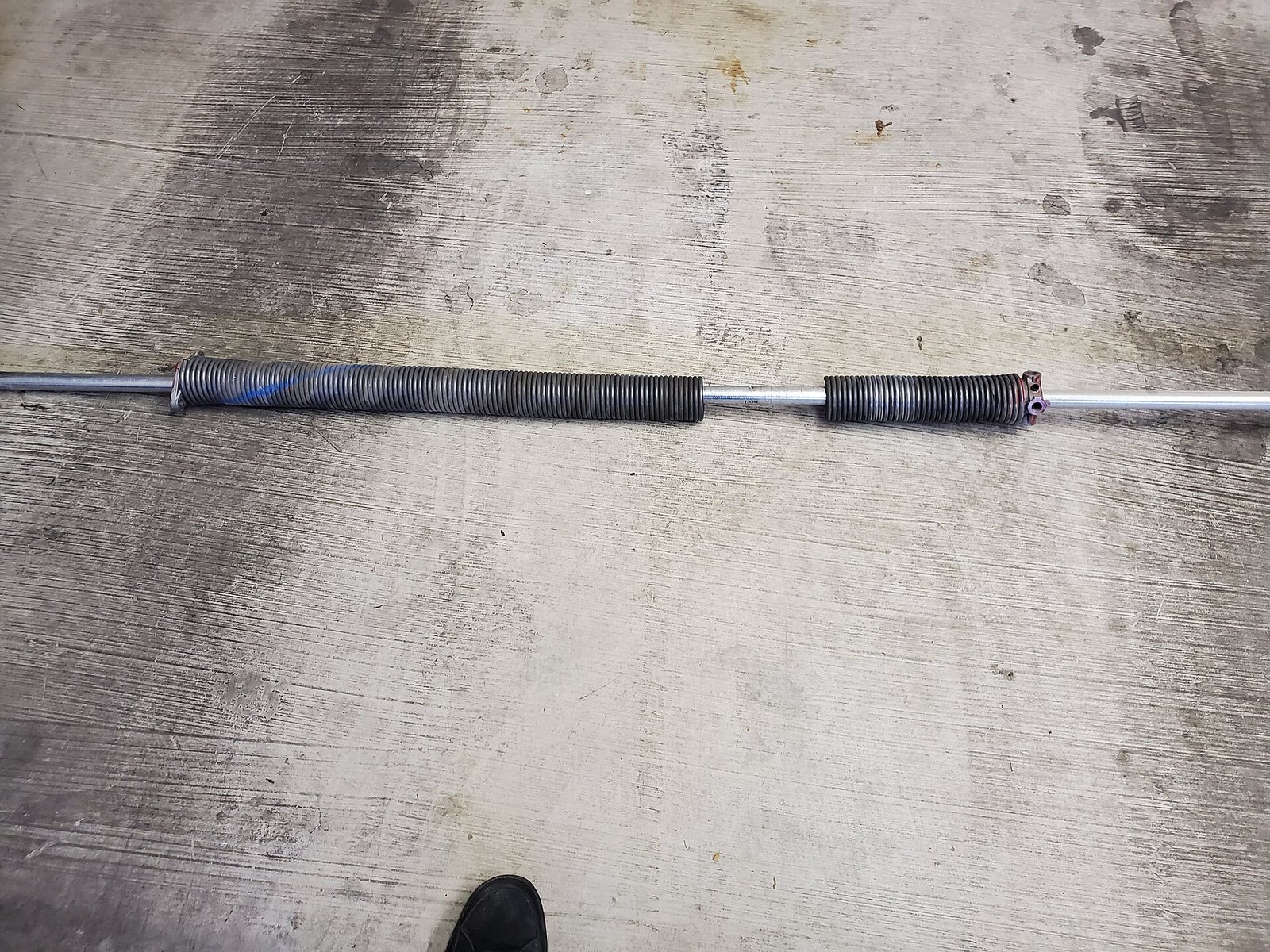 Two broken garage door springs on the ground after being replaced